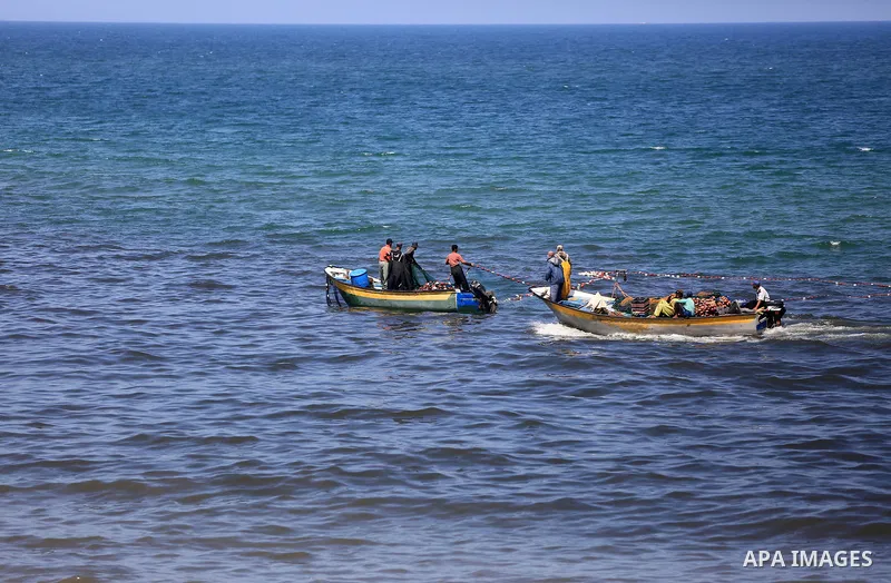 Palestinian fishermen cast a net to catch fishes on a sunny day in the coastal areas, in Gaza City on June 27, 2020. Photo by Ashraf Amra