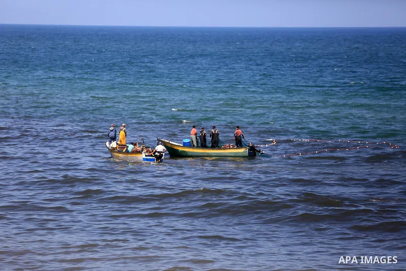 Palestinian fishermen cast a net to catch fishes on a sunny day in the coastal areas, in Gaza City on June 27, 2020. Photo by Ashraf Amra