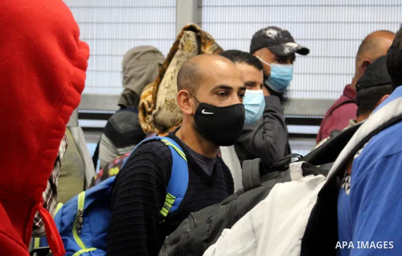 Palestinian labourers wear masks queue to enter Israel through the Mitar checkpoint in the West Bank city of Hebron on June 28, 2020. Photo by Mosab Shawer