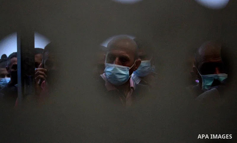 Palestinian labourers wear masks queue to enter Israel through the Mitar checkpoint in the West Bank city of Hebron on June 28, 2020. Photo by Mosab Shawer