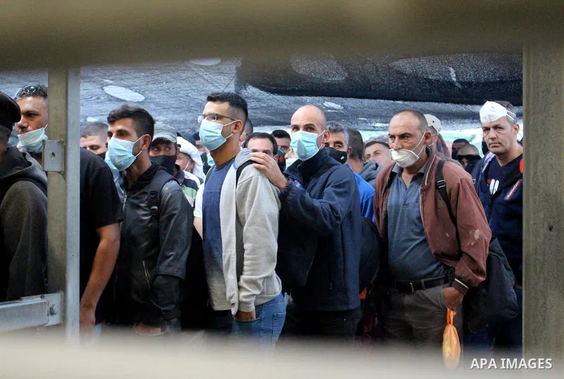 Palestinian labourers wear masks queue to enter Israel through the Mitar checkpoint in the West Bank city of Hebron on June 28, 2020. Photo by Mosab Shawer