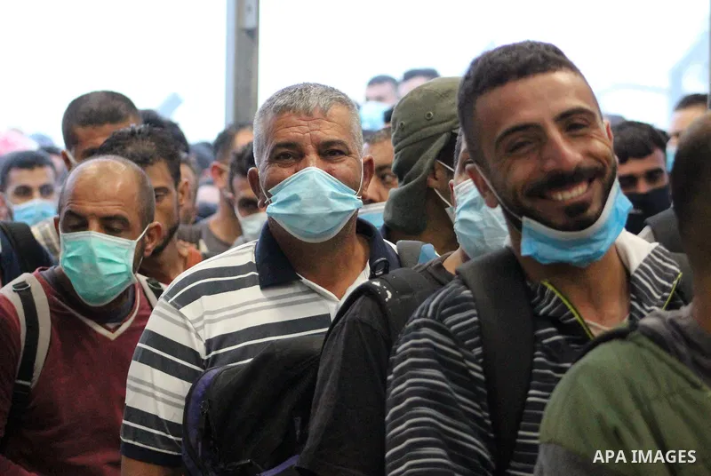 Palestinian labourers wear masks queue to enter Israel through the Mitar checkpoint in the West Bank city of Hebron on June 28, 2020. Photo by Mosab Shawer