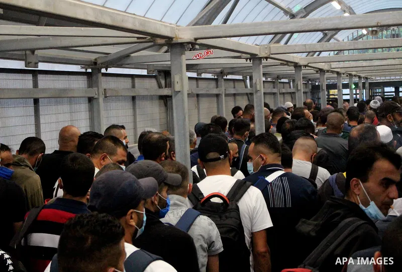 Palestinian labourers wear masks queue to enter Israel through the Mitar checkpoint in the West Bank city of Hebron on June 28, 2020. Photo by Mosab Shawer
