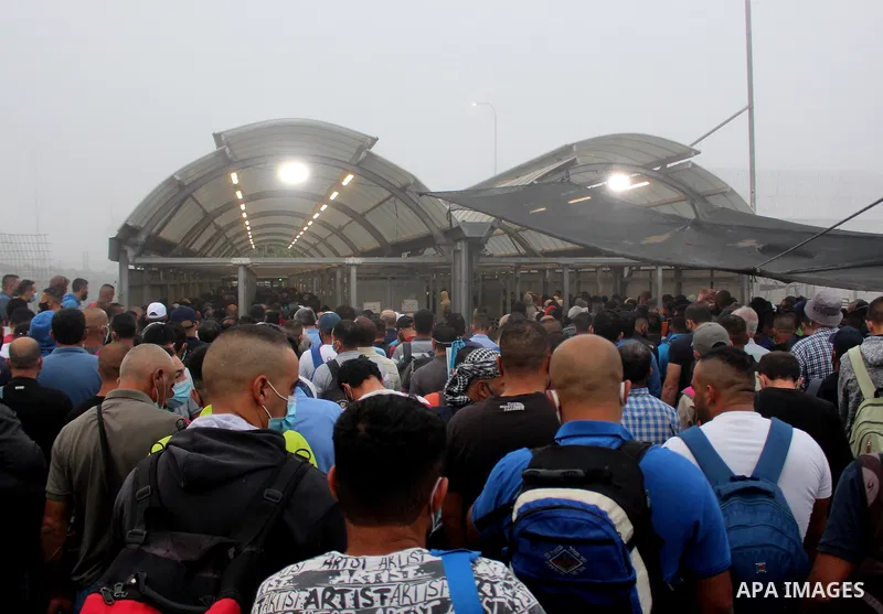 Palestinian labourers wear masks queue to enter Israel through the Mitar checkpoint in the West Bank city of Hebron on June 28, 2020. Photo by Mosab Shawer