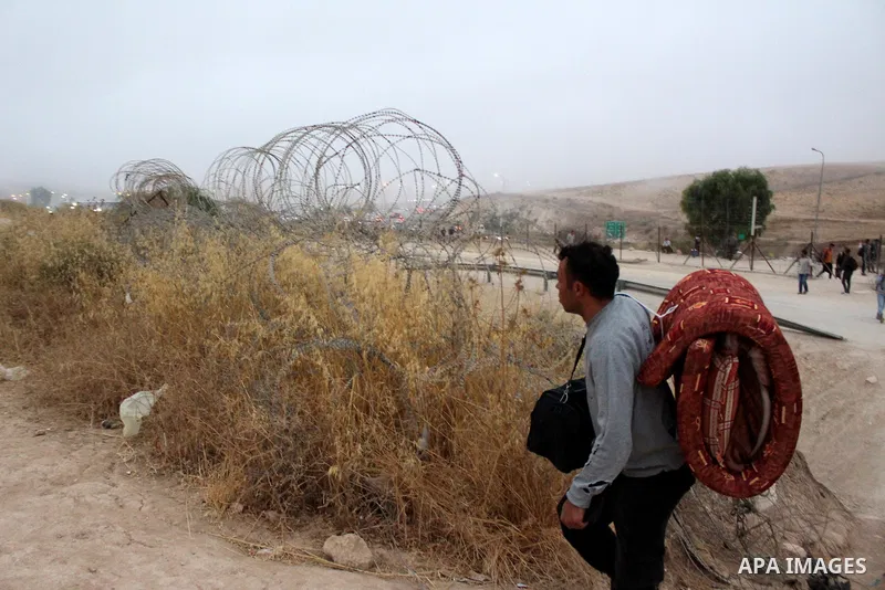 Palestinian labourers wear masks queue to enter Israel through the Mitar checkpoint in the West Bank city of Hebron on June 28, 2020. Photo by Mosab Shawer