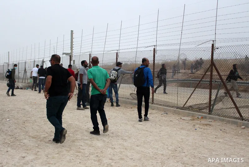Palestinian labourers wear masks queue to enter Israel through the Mitar checkpoint in the West Bank city of Hebron on June 28, 2020. Photo by Mosab Shawer