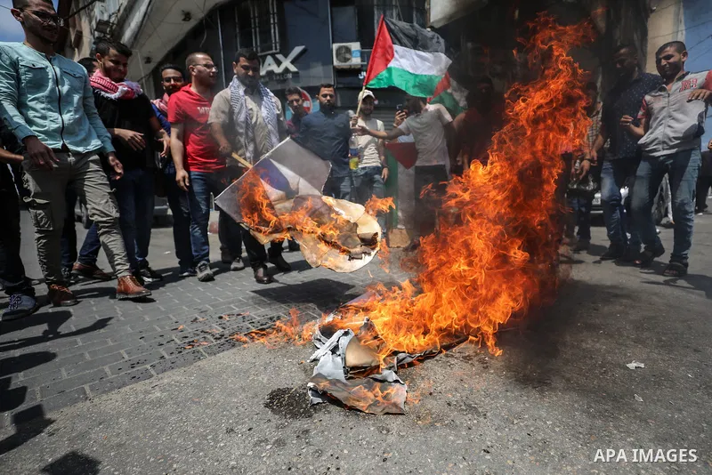 Palestinian protesters burn posters depicting the faces of US President Donald Trump and Israeli Prime Minister Benjamin Netantyahu during a protest against Israel's plans to annex parts of the occupied West Bank, in Gaz...