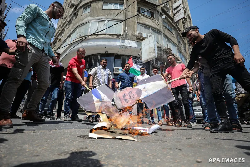 Palestinian protesters burn posters depicting the faces of US President Donald Trump and Israeli Prime Minister Benjamin Netantyahu during a protest against Israel's plans to annex parts of the occupied West Bank, in Gaz...