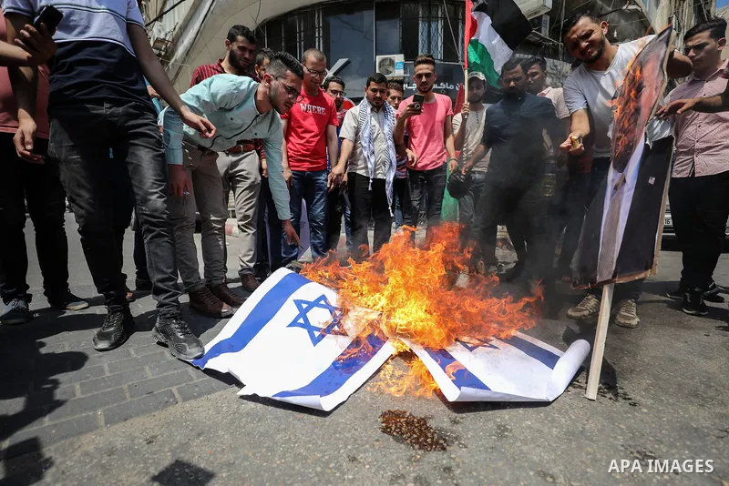 Palestinian protesters burn posters depicting the faces of US President Donald Trump and Israeli Prime Minister Benjamin Netantyahu during a protest against Israel's plans to annex parts of the occupied West Bank, in Gaz...