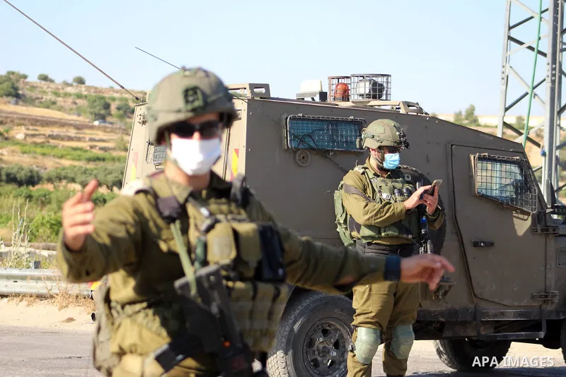 Israeli security forces stand guard as settlers gathern in the mountain of Aljomjoma in the city of Halhul, north of the West Bank of Hebron on June 30, 2020. Photo by Mosab Shawer