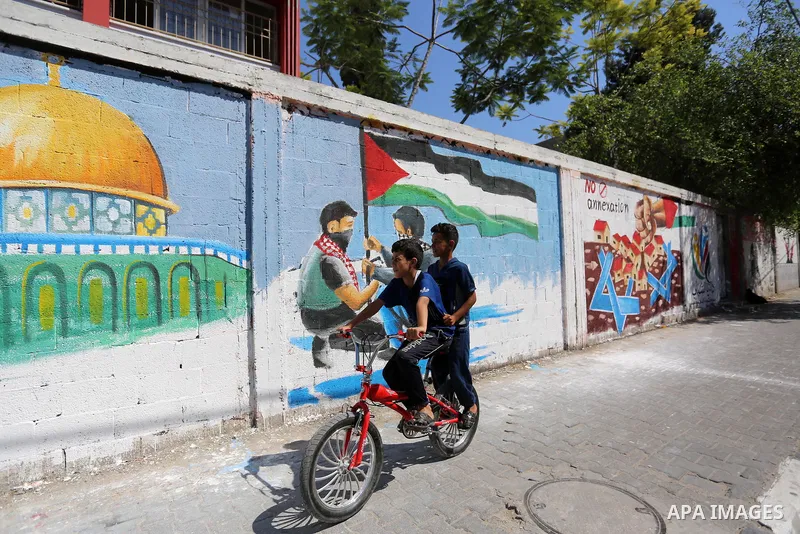 Palestinians walk past a mural against Israel's West Bank annexation plans, in Rafah in the southern Gaza Strip, on July 1, 2020. The government of Israeli Prime Minister Benjamin Netanyahu has said it could begin the pr...