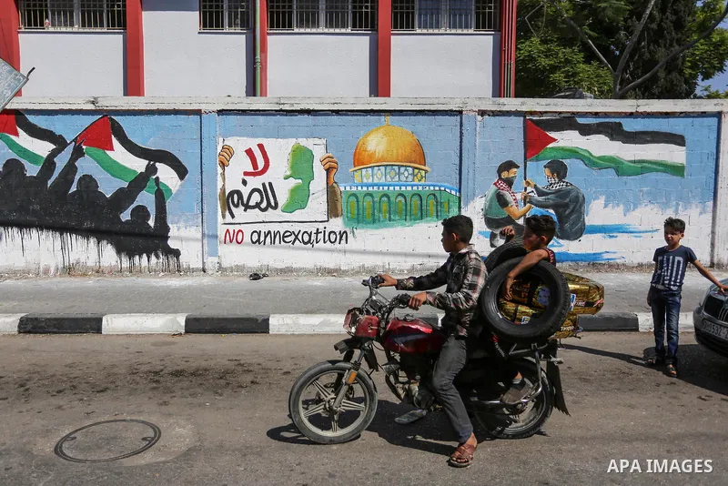 Palestinians walk past a mural against Israel's West Bank annexation plans, in Rafah in the southern Gaza Strip, on July 1, 2020. The government of Israeli Prime Minister Benjamin Netanyahu has said it could begin the pr...