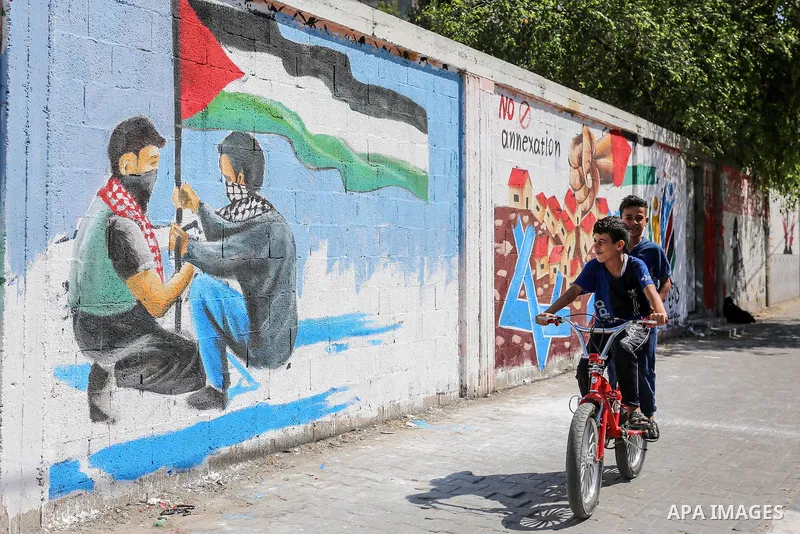 Palestinians walk past a mural against Israel's West Bank annexation plans, in Rafah in the southern Gaza Strip, on July 1, 2020. The government of Israeli Prime Minister Benjamin Netanyahu has said it could begin the pr...