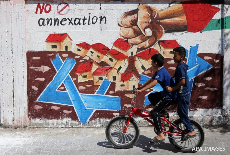 Palestinians walk past a mural against Israel's West Bank annexation plans, in Rafah in the southern Gaza Strip, on July 1, 2020. The government of Israeli Prime Minister Benjamin Netanyahu has said it could begin the pr...