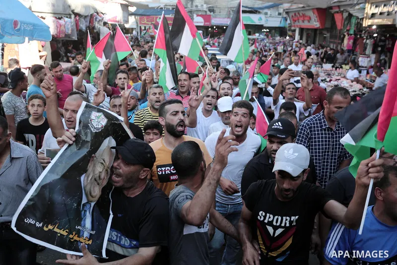 Palestinians waves national flags and hold posters of Palestinian President Mahmud Abbas during a demonstration against Israel's West Bank annexation plans in Khan Younis in the southern Gaza Strip, on July 2, 2020. Isra...