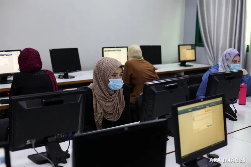 Palestinian graduates wearing a face mask as a preventive measure amid fears of the spread of the coronavirus disease (COVID-19), sit in a hall to solve employment exams to get a job, in Gaza city on, July 5, 2020. Photo...