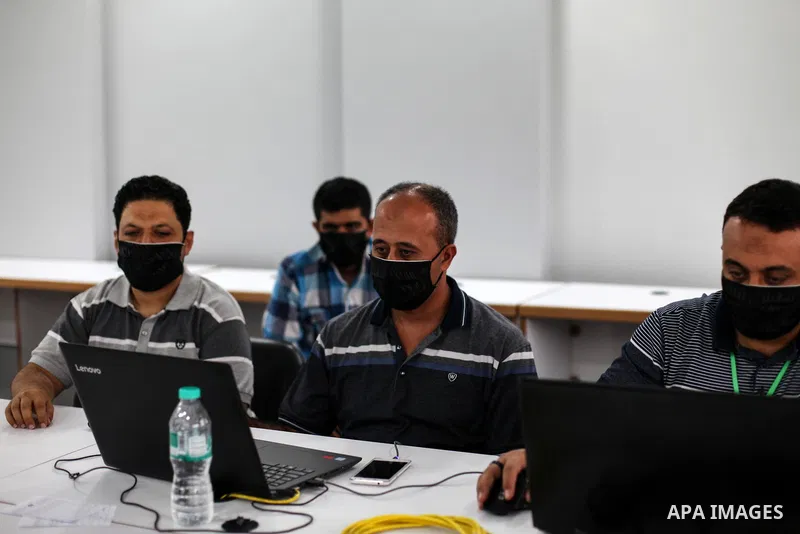 Palestinian graduates wearing a face mask as a preventive measure amid fears of the spread of the coronavirus disease (COVID-19), sit in a hall to solve employment exams to get a job, in Gaza city on, July 5, 2020. Photo...
