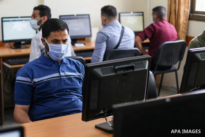 Palestinian graduates wearing a face mask as a preventive measure amid fears of the spread of the coronavirus disease (COVID-19), sit in a hall to solve employment exams to get a job, in Gaza city on, July 5, 2020. Photo...