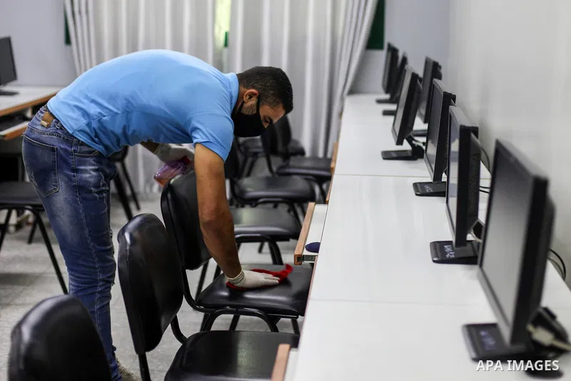 Palestinian workers wearing a face mask as a preventive measure amid fears of the spread of the coronavirus disease (COVID-19), disinfect a hall for the employment exams in Gaza city on, July 5, 2020. Photo by Mahmoud Aj...