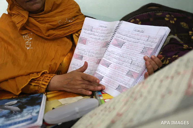 A Palestinian woman, Mimi Faraj Allah, 57, writes a copy of the Holy Quran, at her house, in al-Nusirat refugee camp in the central Gaza strip, on July 28, 2020. Photo by Ashraf Amra