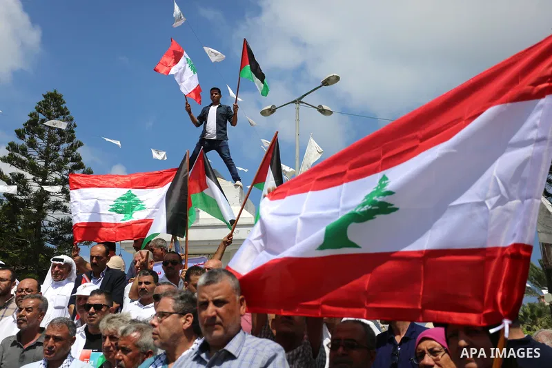Palestinians hold Lebanese flags during a rally to show solidarity with the Lebanese people following the huge explosions in Beirut's port area, in Gaza City, on August 6, 2020. Photo by Ashraf Amra