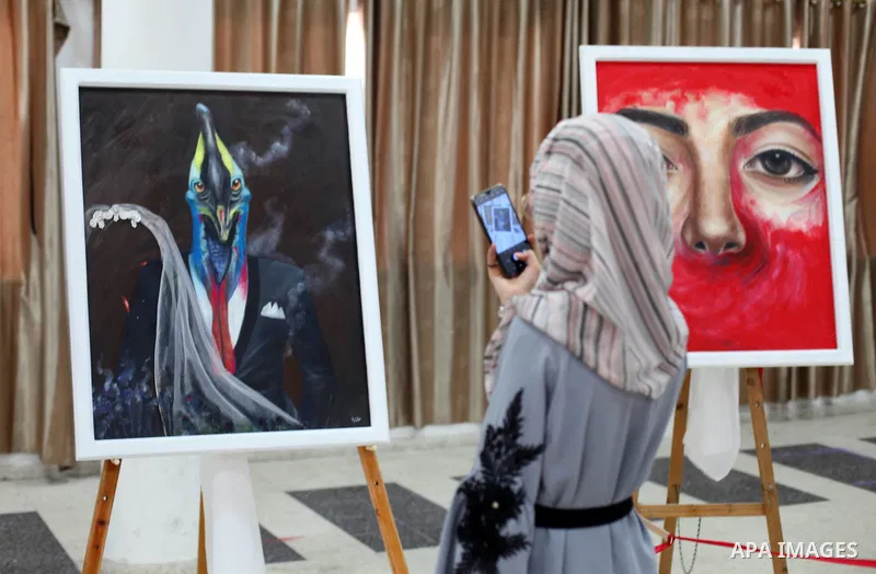 Palestinians visit the artist's exhibition Kholoud Al-Dessouki, 28, her two-day to reveal the violence against women through dozens of paintings on display in Gaza City on August 13, 2020. Photo by Mahmoud Ajjour