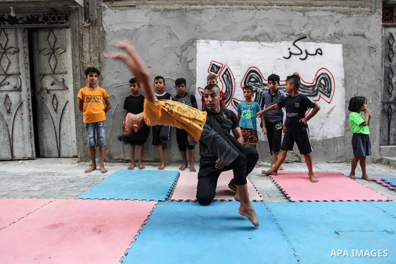 Palestinian parkour trainer Ahmed Abu Hasira "myuz",35, trains children outside his home, in Gaza City on August 18, 2020. Parkour is an activity that can be practiced alone or with others and is usually carried out in u...