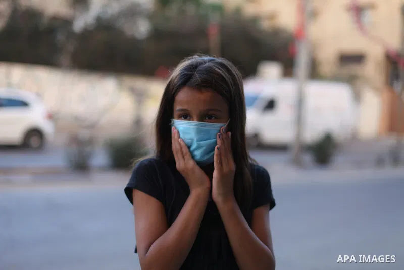 Palestinians wear face masks as they walk in a street during a 48 hour lockdown imposed following the discovery of the first coronavirus cases in the Gaza Strip, in Gaza City on August 25, 2020. Photo by Mahmoud Ajjour