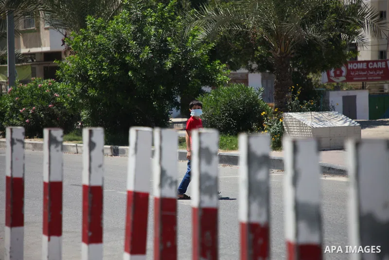Palestinians wearing a protective masks against the spread of the coronavirus Covid-19, walk in a street during lockdown in Gaza City on August 27, 2020 amid increasing cases of infection in the Palestinian enclave. The...