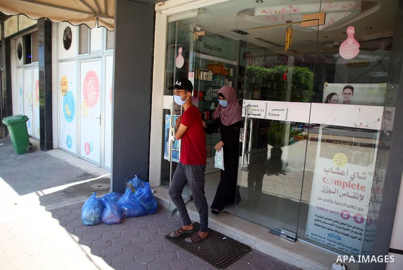 Palestinians wearing a protective masks against the spread of the coronavirus Covid-19, walk in a street during lockdown in Gaza City on August 27, 2020 amid increasing cases of infection in the Palestinian enclave. The...
