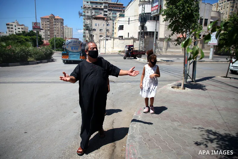 Palestinians wearing a protective masks against the spread of the coronavirus Covid-19, walk in a street during lockdown in Gaza City on August 27, 2020 amid increasing cases of infection in the Palestinian enclave. The...