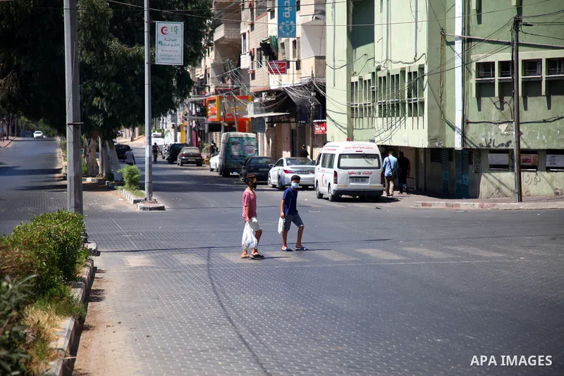 Palestinians wearing a protective masks against the spread of the coronavirus Covid-19, walk in a street during lockdown in Gaza City on August 27, 2020 amid increasing cases of infection in the Palestinian enclave. The...