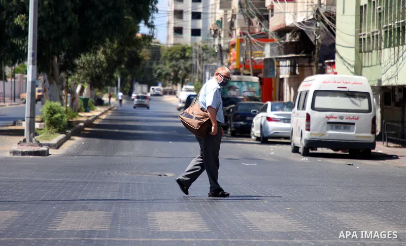 Palestinians wearing a protective masks against the spread of the coronavirus Covid-19, walk in a street during lockdown in Gaza City on August 27, 2020 amid increasing cases of infection in the Palestinian enclave. The...