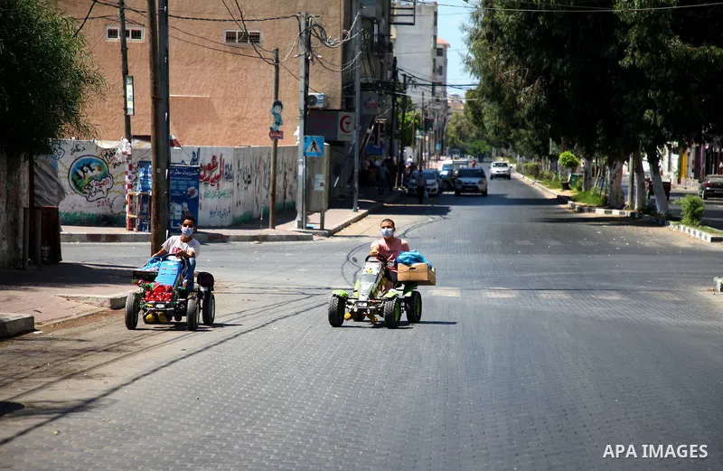 Palestinians wearing a protective masks against the spread of the coronavirus Covid-19, walk in a street during lockdown in Gaza City on August 27, 2020 amid increasing cases of infection in the Palestinian enclave. The...