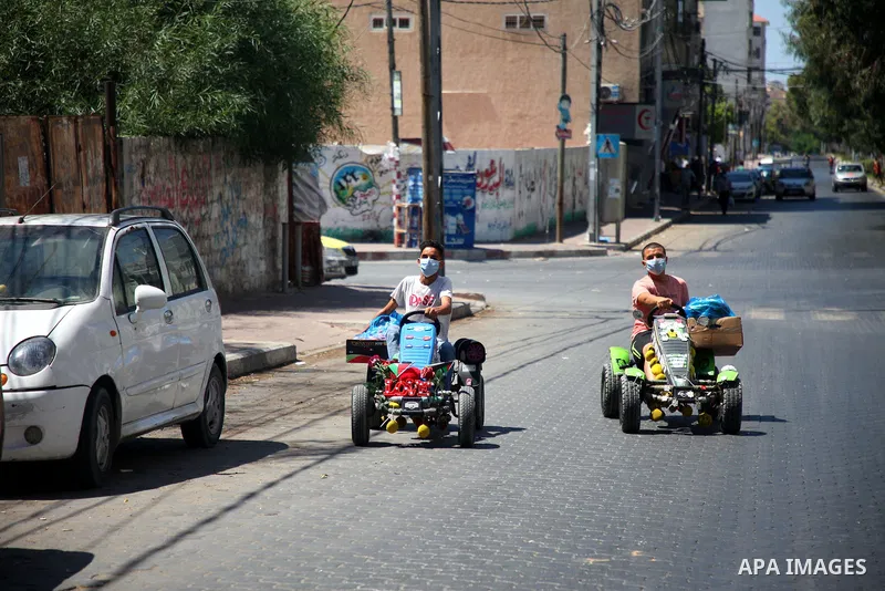Palestinians wearing a protective masks against the spread of the coronavirus Covid-19, walk in a street during lockdown in Gaza City on August 27, 2020 amid increasing cases of infection in the Palestinian enclave. The...