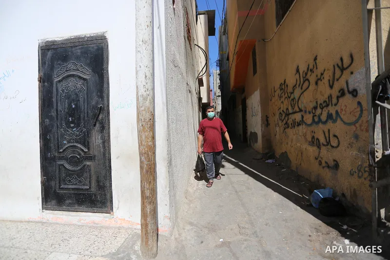 Palestinians wear face masks as they walk in a street during the imposed lockdown to mitigate virus outbreak in the Gaza Strip, in Dair Al Balah in the central of Gaza Strip on August 27, 2020, during a lockdown in the P...