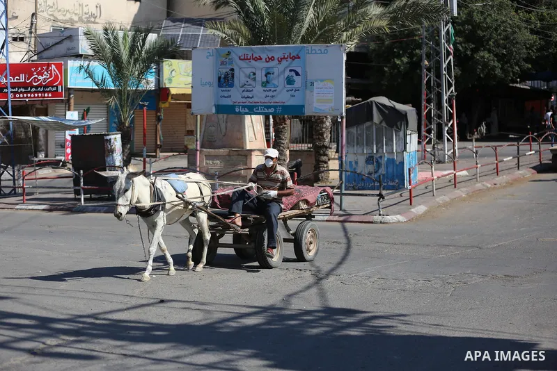 Palestinians wear face masks as they walk in a street during the imposed lockdown to mitigate virus outbreak in the Gaza Strip, in Dair Al Balah in the central of Gaza Strip on August 27, 2020, during a lockdown in the P...