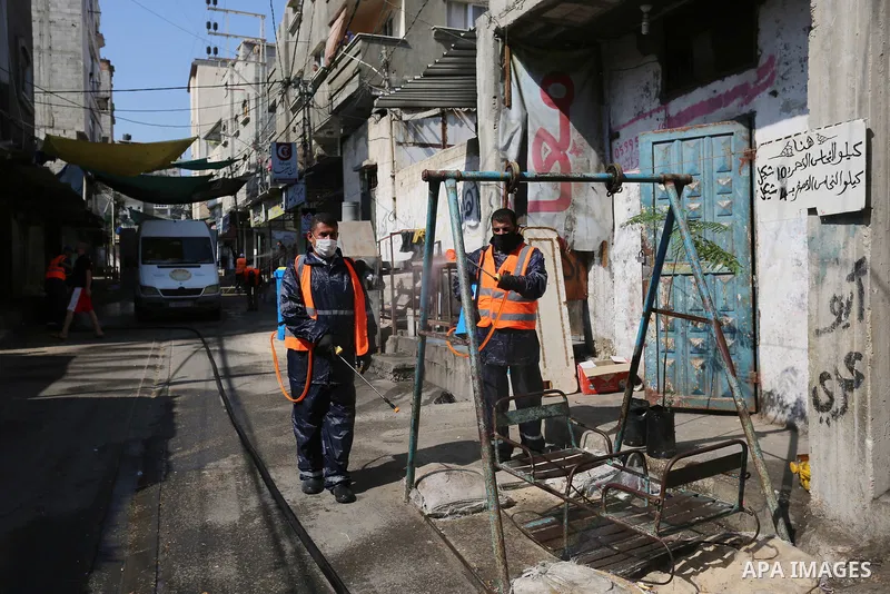 Palestinian workers wearing protective gear, disinfect a streets, during the imposed lockdown to mitigate virus outbreak in Dair Al Balah in the central of Gaza Strip, on August 29, 2020, during a lockdown in the Palesti...
