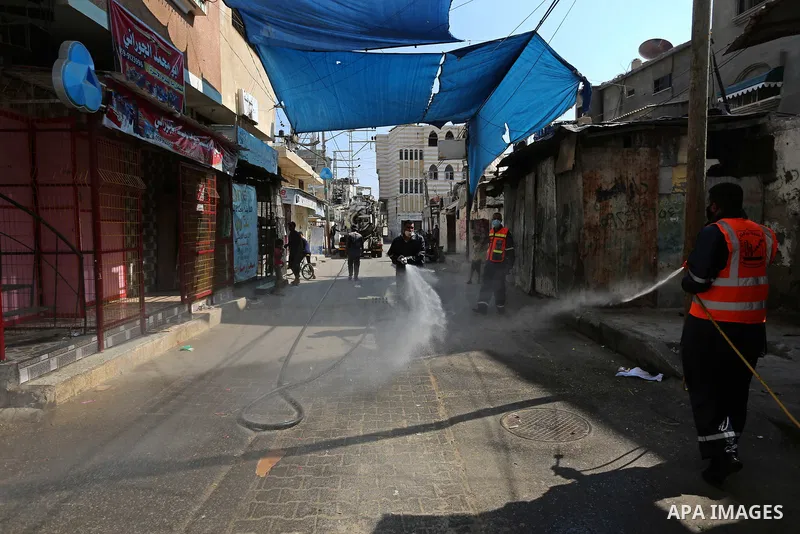 Palestinian workers wearing protective gear, disinfect a streets, during the imposed lockdown to mitigate virus outbreak in Dair Al Balah in the central of Gaza Strip, on August 29, 2020, during a lockdown in the Palesti...