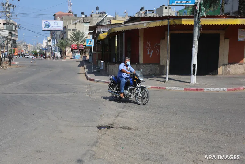 Palestinians wear face masks as they walk in a street during the imposed lockdown to mitigate virus outbreak in the Gaza Strip, in Dair Al Balah in the central of Gaza Strip on August 30, 2020. Photo by Ashraf Amra