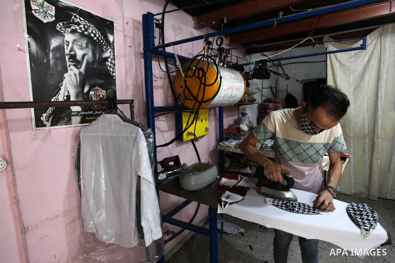 Palestinian tailor, Sherif Al-Yaqoubi, 27, makes protective masks depicting a Palestinian keffiyeh in his sewing workshop in Gaza city on September 3, 2020. Photo by Mahmoud Ajjour