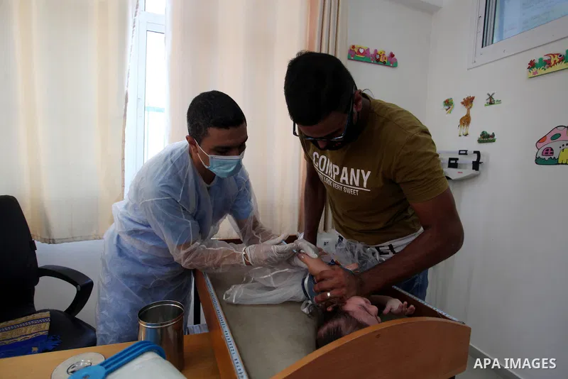 A UNRWA employee wears face mask as he provides Polio vaccine and Rota virus vaccines for children in a clinic in Bureij refugee camp central of Gaza Strip on September 9, 2020. Photo by Mahmoud Ajjour