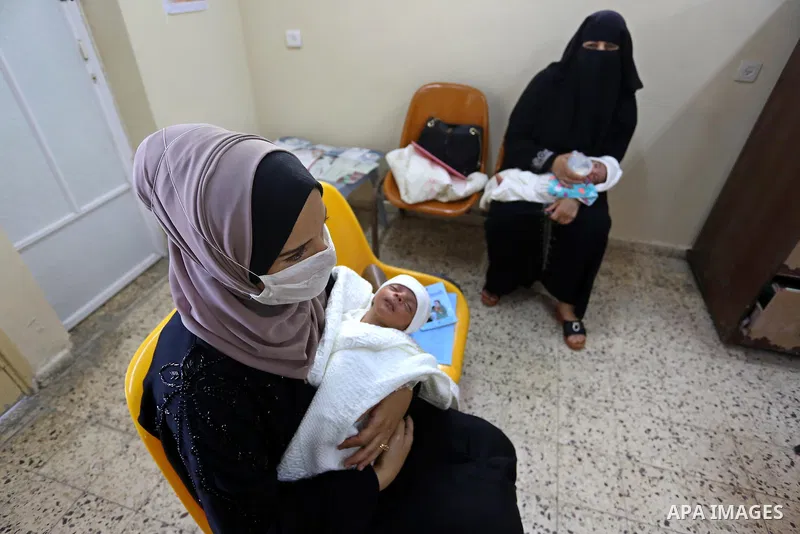Palestinian women mask-clad due to the Covid-19 coronavirus pandemic wait with their children to take Polio vaccine and Rota virus vaccines at a health center in Dair Al Balah in the central of Gaza Strip, on Sept. 9, 20...