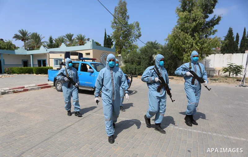Palestinian policemen wearing protective gear, guard a barrier blocking a road, in Deir Al-Balah, in the center of the Gaza Strip, on Sept. 10, 2020, during a lockdown amid the COVID-19 pandemic. Photo by Ashraf Amra