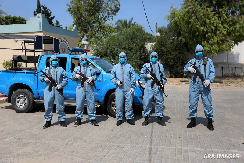 Palestinian policemen wearing protective gear, guard a barrier blocking a road, in Deir Al-Balah, in the center of the Gaza Strip, on Sept. 10, 2020, during a lockdown amid the COVID-19 pandemic. Photo by Ashraf Amra