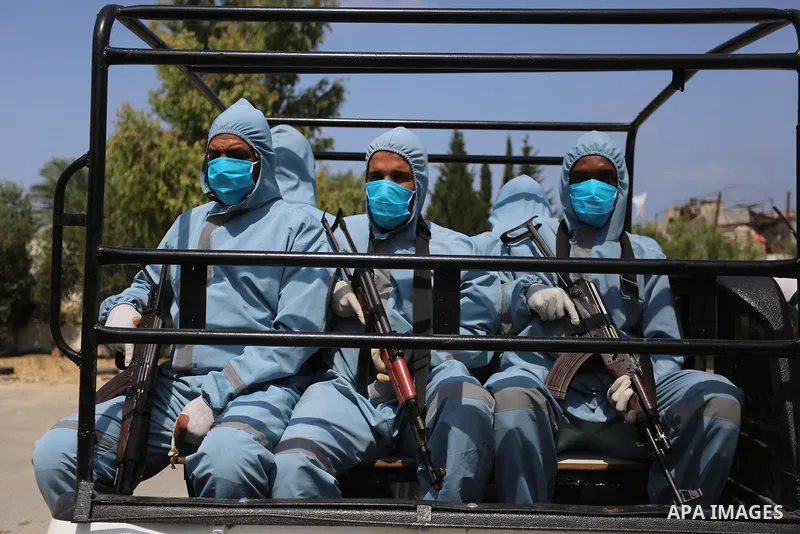 Palestinian policemen wearing protective gear, guard a barrier blocking a road, in Deir Al-Balah, in the center of the Gaza Strip, on Sept. 10, 2020, during a lockdown amid the COVID-19 pandemic. Photo by Ashraf Amra