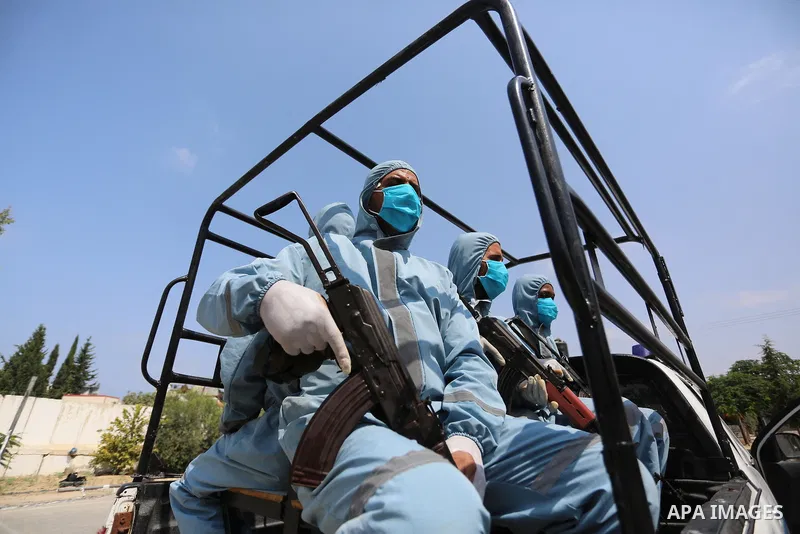 Palestinian policemen wearing protective gear, guard a barrier blocking a road, in Deir Al-Balah, in the center of the Gaza Strip, on Sept. 10, 2020, during a lockdown amid the COVID-19 pandemic. Photo by Ashraf Amra