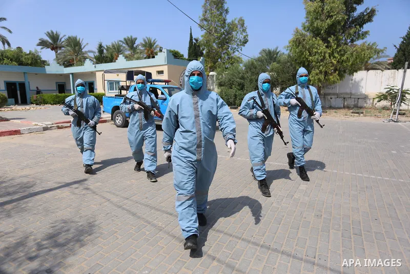 Palestinian policemen wearing protective gear, guard a barrier blocking a road, in Deir Al-Balah, in the center of the Gaza Strip, on Sept. 10, 2020, during a lockdown amid the COVID-19 pandemic. Photo by Ashraf Amra