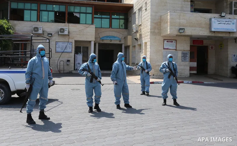 Palestinian policemen wearing protective gear, guard a barrier blocking a road, in Deir Al-Balah, in the center of the Gaza Strip, on Sept. 10, 2020, during a lockdown amid the COVID-19 pandemic. Photo by Ashraf Amra