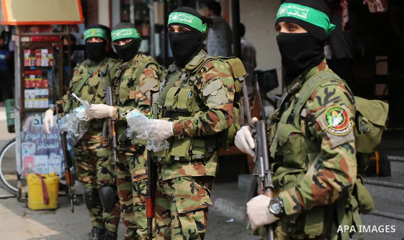 Palestinian members of al-Qassam Brigades, the armed wing of the Hamas movement, distribute protective masks to people on the street amid the Covid-19 coronavirus pandemic, in Nuseirat in the central of Gaza Strip on Sep...